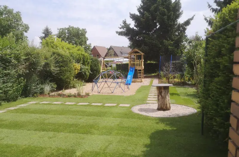 Weitläufiger Garten mit frisch verlegtem Rollrasen, Trittplatten und Spielbereich
