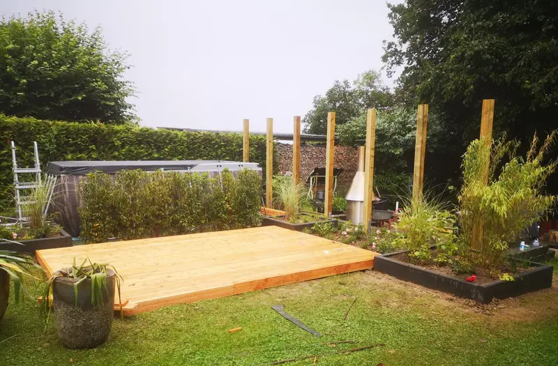 Terrassenprojekt während der Bauphase: Holzpodest mit Pergola-Pfosten und frisch gesetzten Hochbeeten